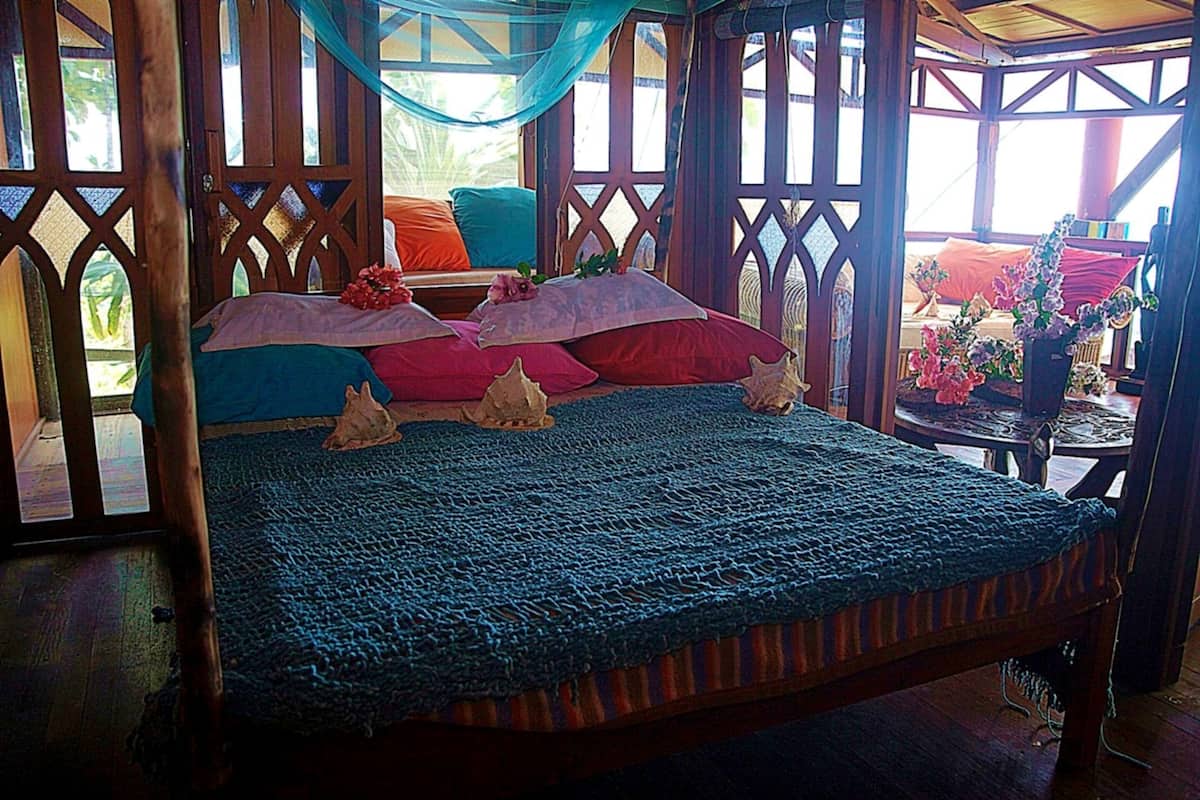 Una cama con una colcha azul, cabecera de madera y almohadones decorativos.