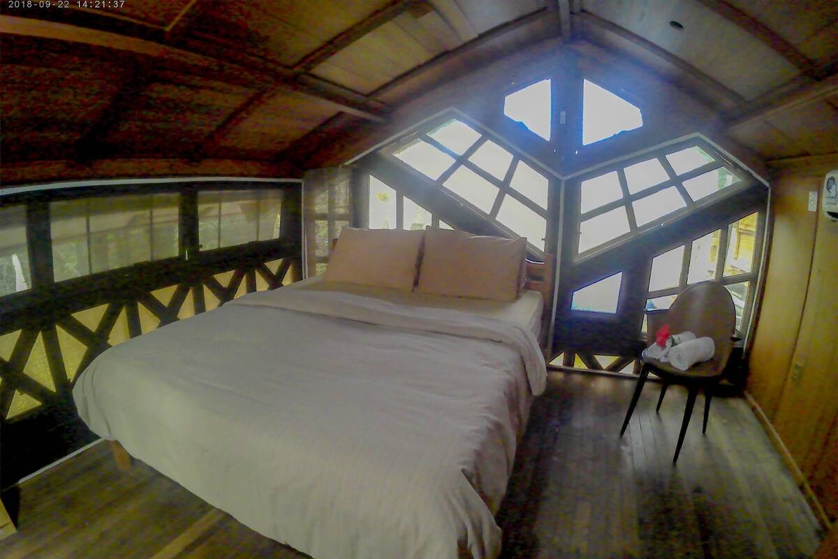 Un dormitorio con una cama grande, una silla y una ventana con vistas.