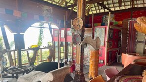 Una habitación con techo de madera, un ventanal grande y una mesa con un tapete tejido.