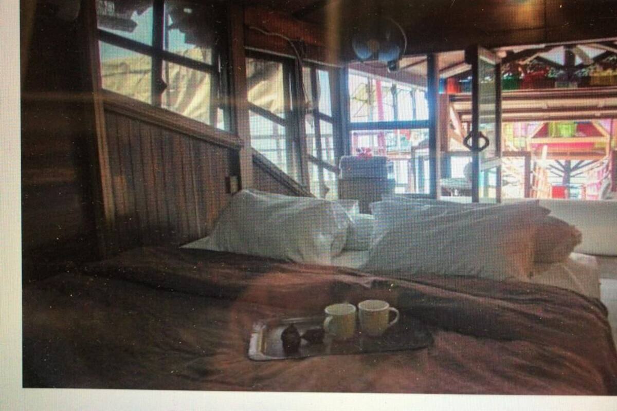Una habitación acogedora con una cama, una bandeja con dos tazas y un ventanal con vistas a un edificio colorido.