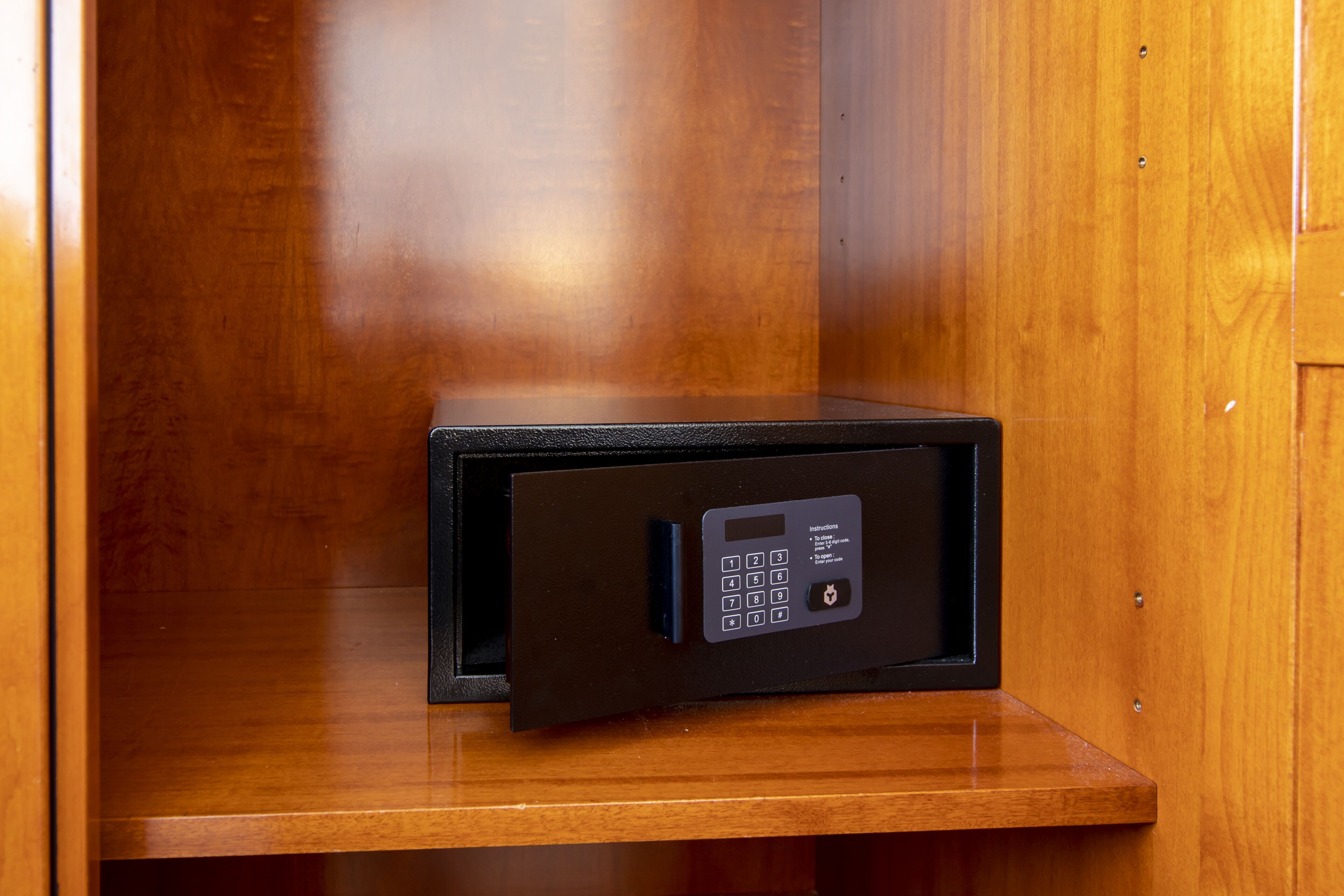A black safe with a keypad, installed in a wooden cabinet.