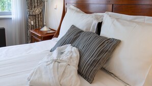 A neatly made bed with white and striped pillows, a wooden headboard, and a bedside table with a lamp.