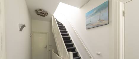 A staircase with white railings and dark steps leading to a door.
