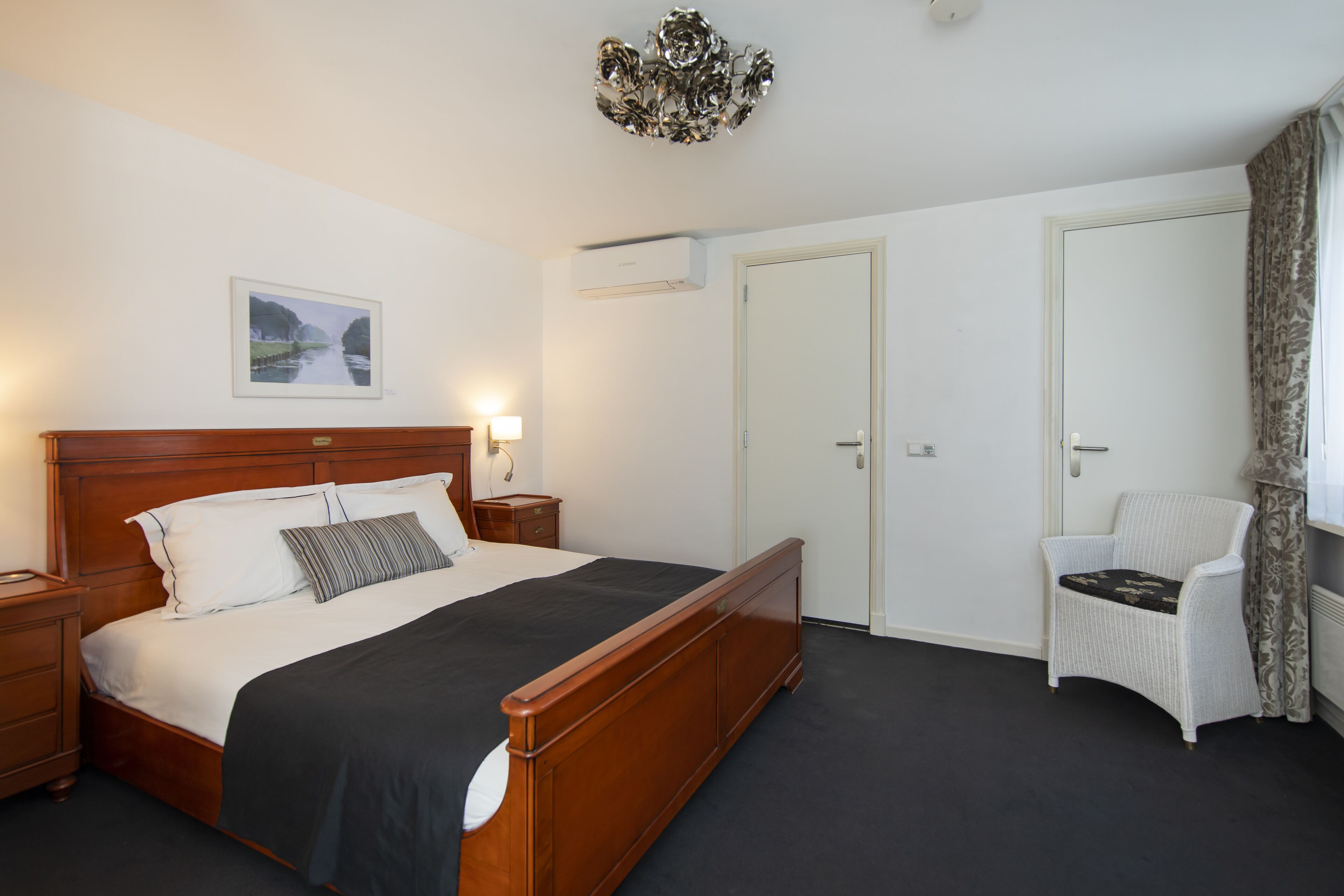 Quarto com cama de madeira, uma cadeira, uma porta e ar-condicionado fixado na parede.