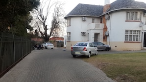 A paved driveway leading to a white building with a curved roof and satellite dishes. - LTN Lodge (Johannesburg)