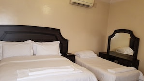 A hotel room with two beds, a dark wooden headboard, a small bedside table, a nightstand, a mirror, and an air conditioning unit. - LTN Lodge (Johannesburg)