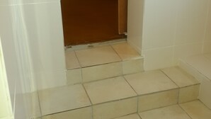 A staircase leading to a room with white tiled walls and a brown carpeted floor. - LTN Lodge (Johannesburg)