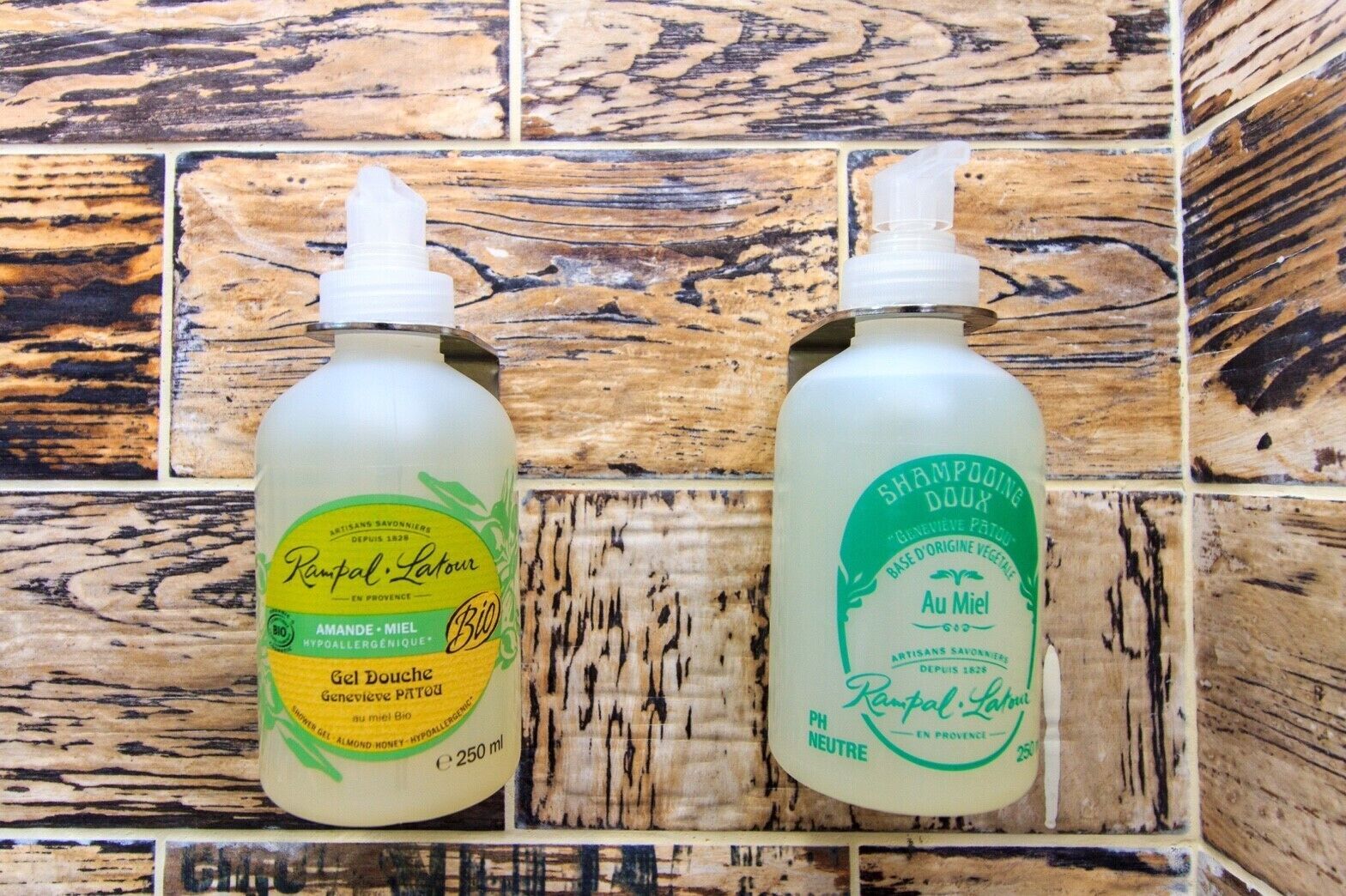 Two bottles of shampoo on a wooden shelf.
