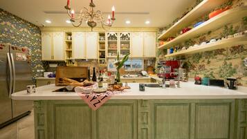 A kitchen with a central island, decorative wallpaper, and a chandelier.