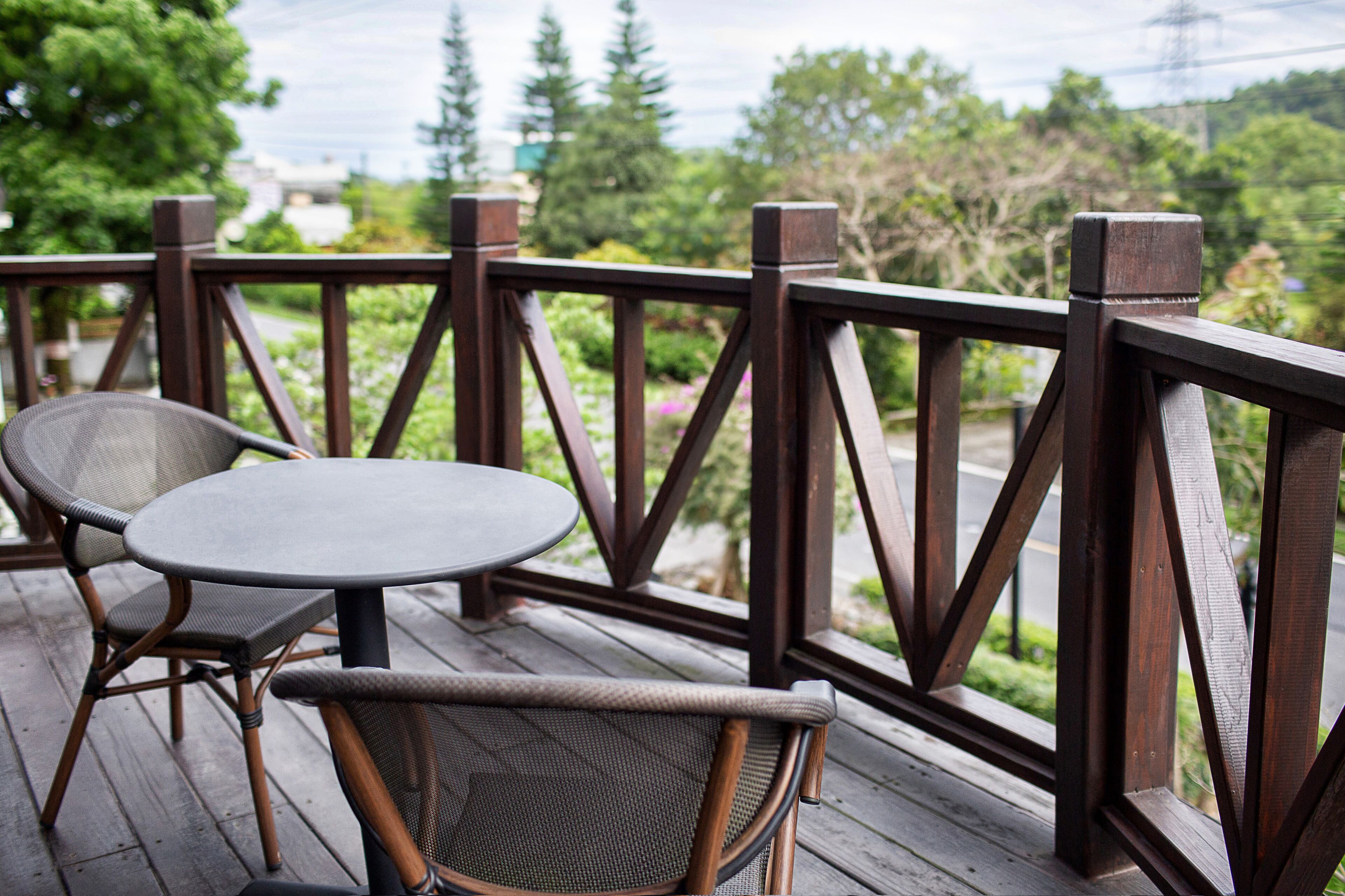 A wooden deck with two wicker chairs and a small round table.
