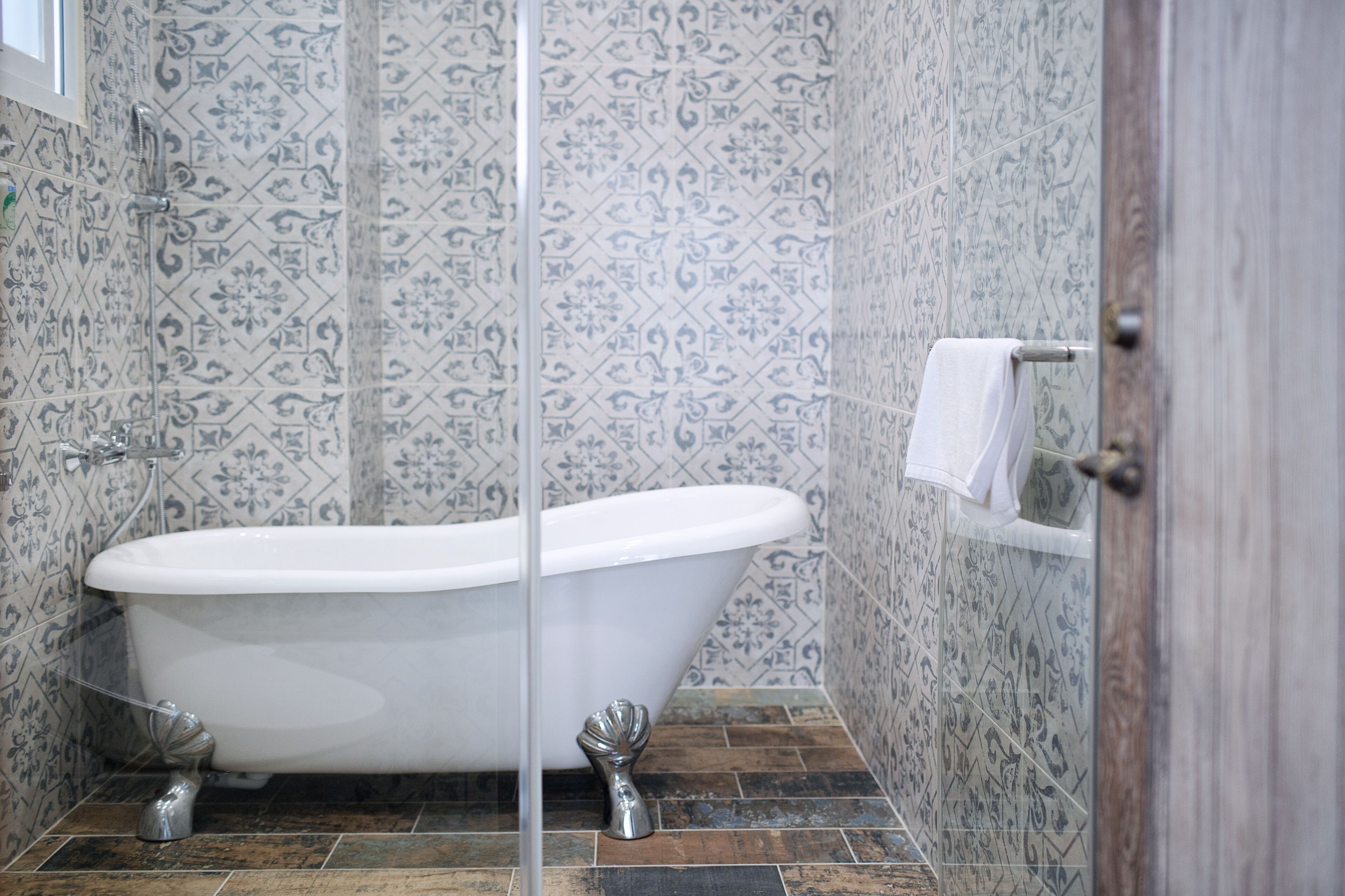 Une salle de bain avec une baignoire sur pieds, des murs carrelés et une porte en bois.