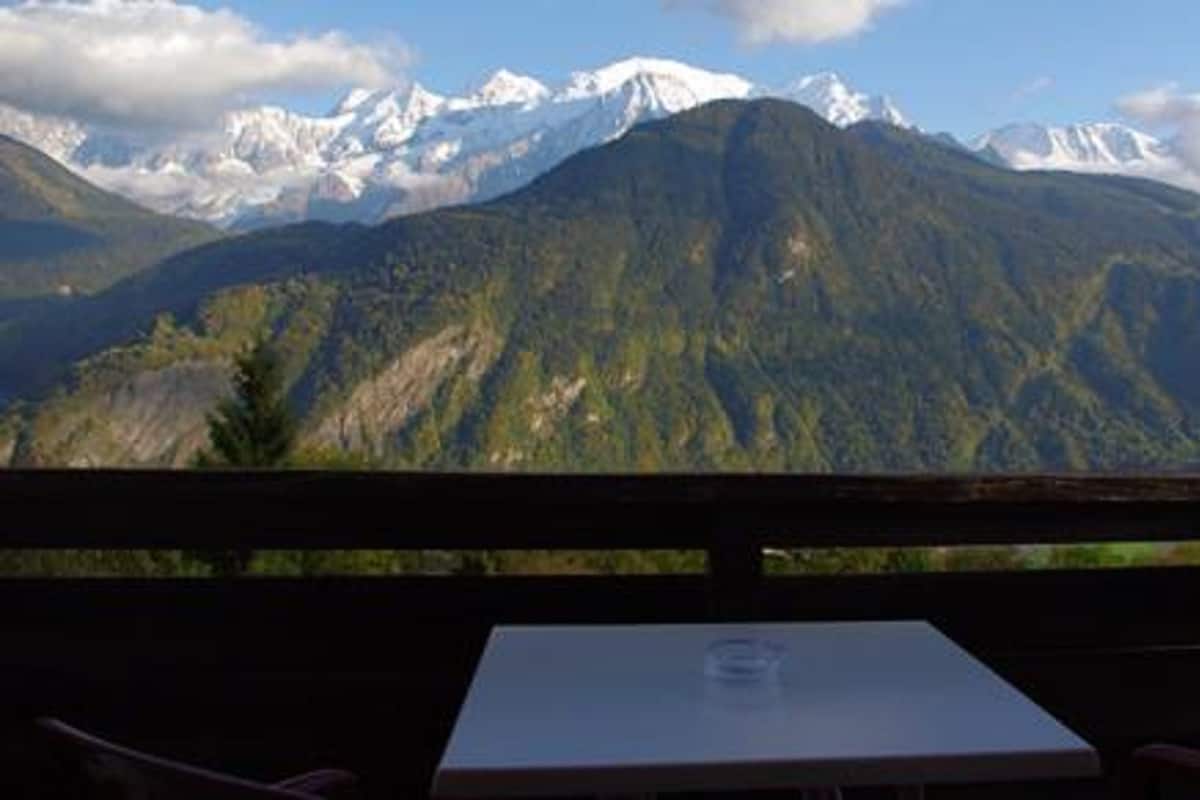 A mountain view from a balcony with a table and chairs.