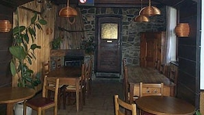 Un intérieur rustique avec des tables et des chaises en bois, des murs en pierre et des suspensions en cuivre.