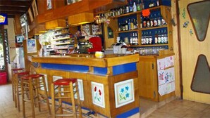 Un espace bar avec des tabourets de bar en bois, des étagères remplies de bouteilles et un comptoir.