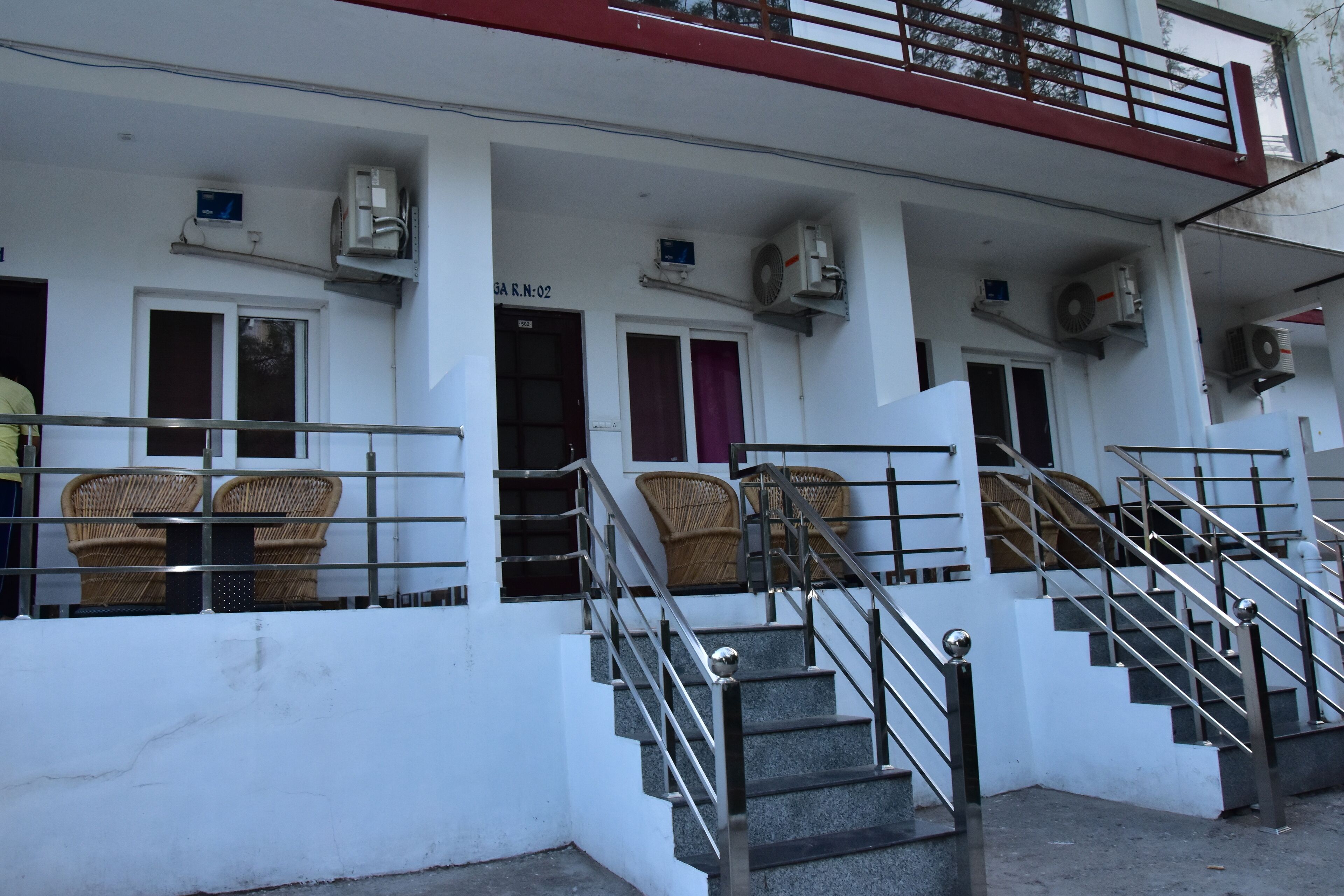 A building with a staircase, wicker furniture, and air conditioning units.