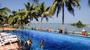 Una piscina con sillones de descanso y palmeras.