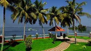 Un jardín tranquilo con palmeras, un pabellón y vistas al agua.