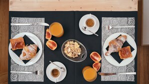 A breakfast setup with croissants, fruit, and coffee on a black tablecloth with a wooden table. - Garage Bonci B&B (Pietrasanta)