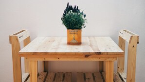 A wooden table with a potted plant on top, surrounded by wooden chairs. - Garage Bonci B&B (Pietrasanta)