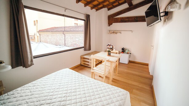 A bedroom with a bed, wooden desk, and a television on the wall. - Garage Bonci B&B (Pietrasanta)