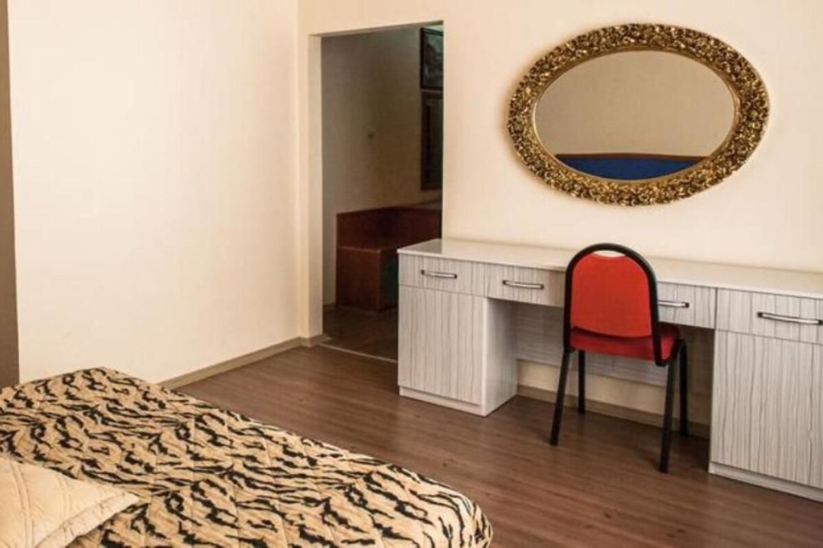 Ein Schlafzimmer mit einem Bett, einem Schreibtisch, einem Stuhl und einem Kleiderschrank.