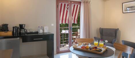A compact kitchen with a refrigerator, coffee maker, and a dining area with a table set for breakfast.