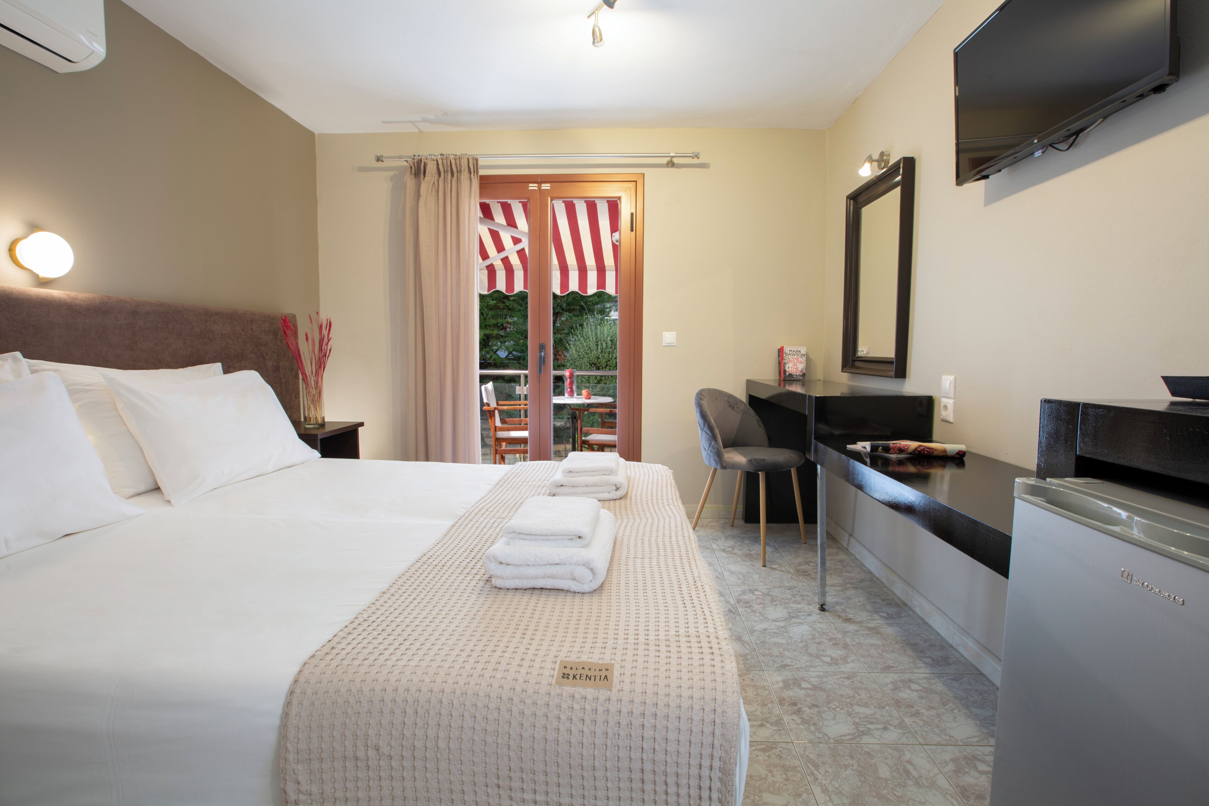 Una habitación de hotel con una cama, un escritorio, una silla, un televisor y un mini bar.
