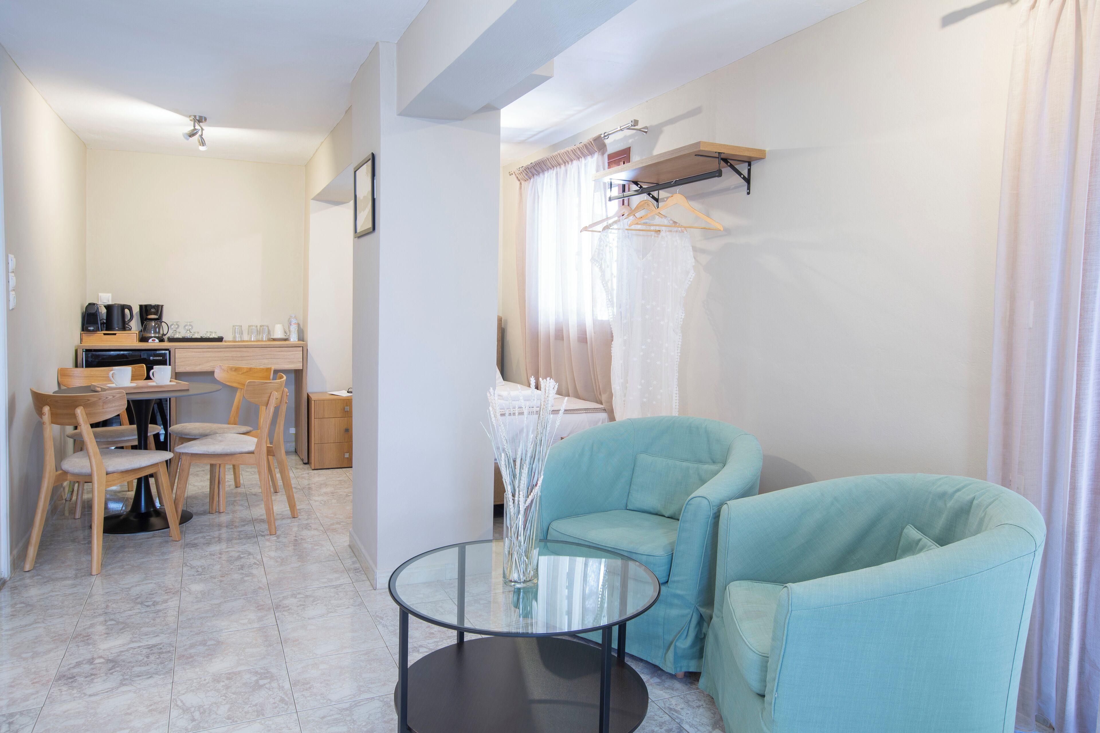 Une pièce moderne comprenant une table à manger, des chaises, un canapé, une petite table avec un vase et un porte-manteau mural.
