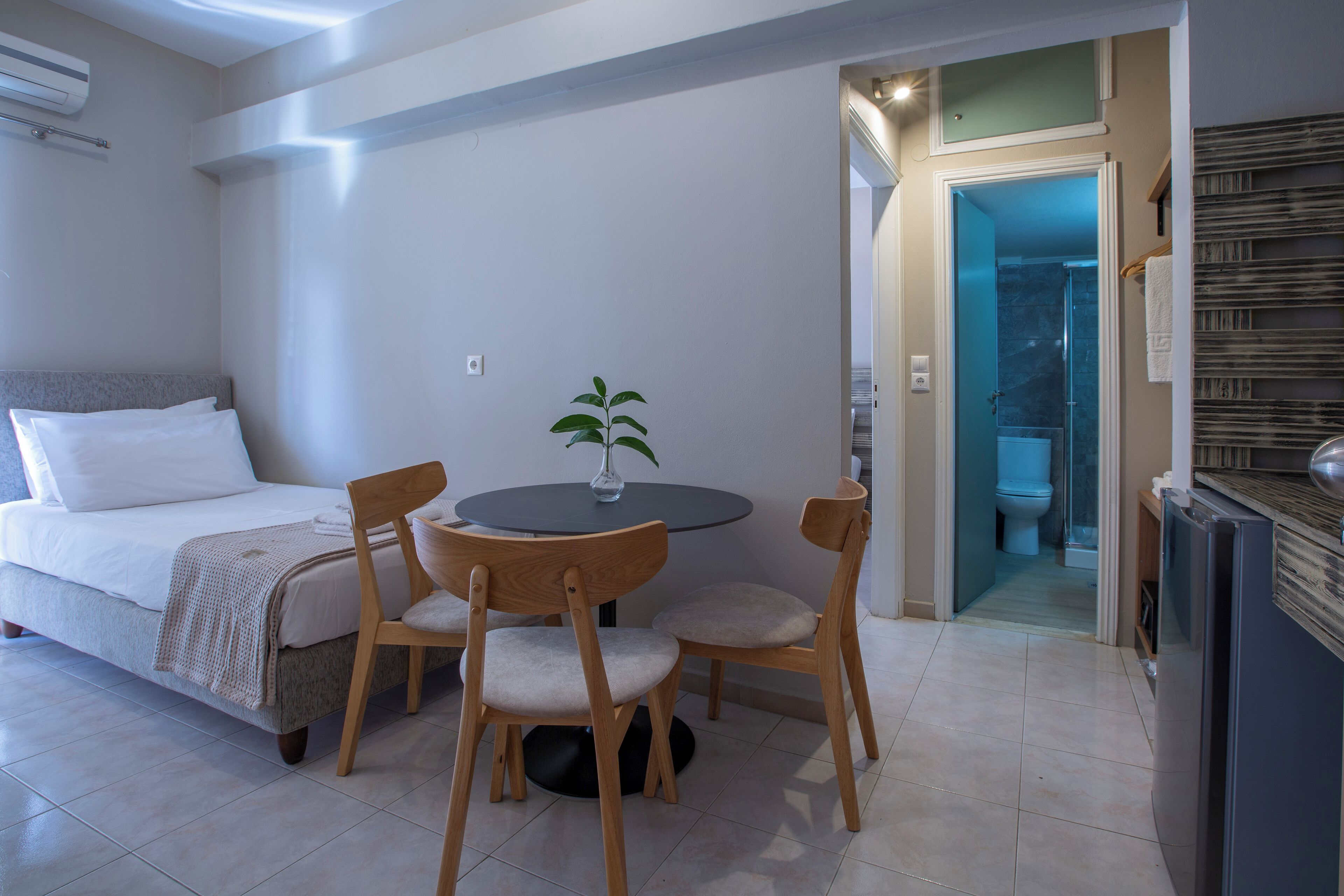 Un dormitorio con cama, mesita de noche y una pequeña mesa redonda con sillas.
