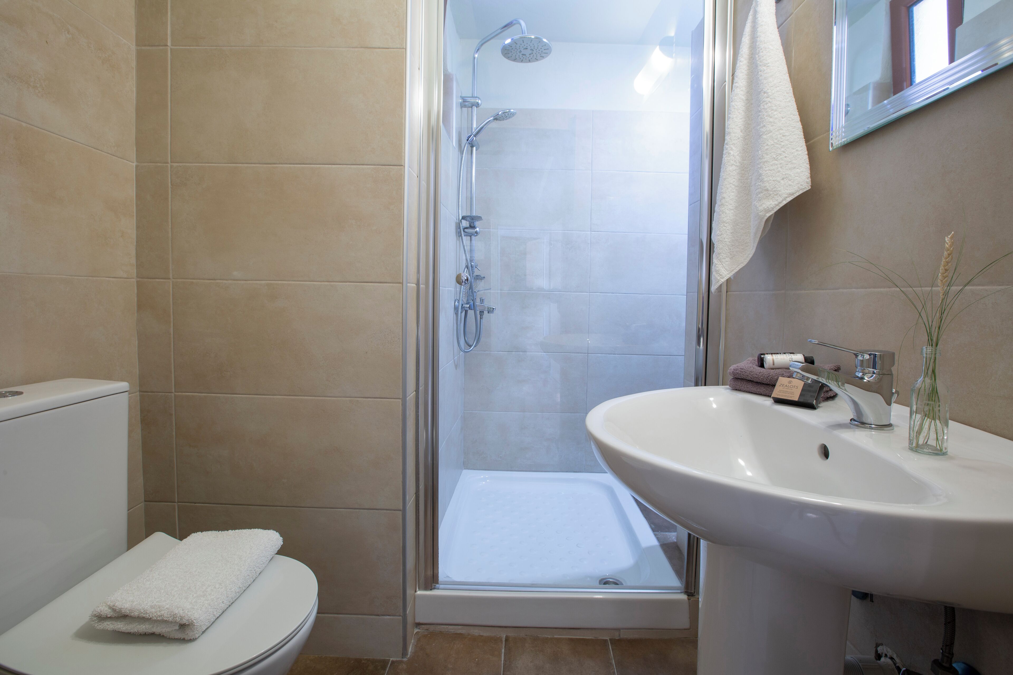 Een badkamer met douche, toilet en wastafel.