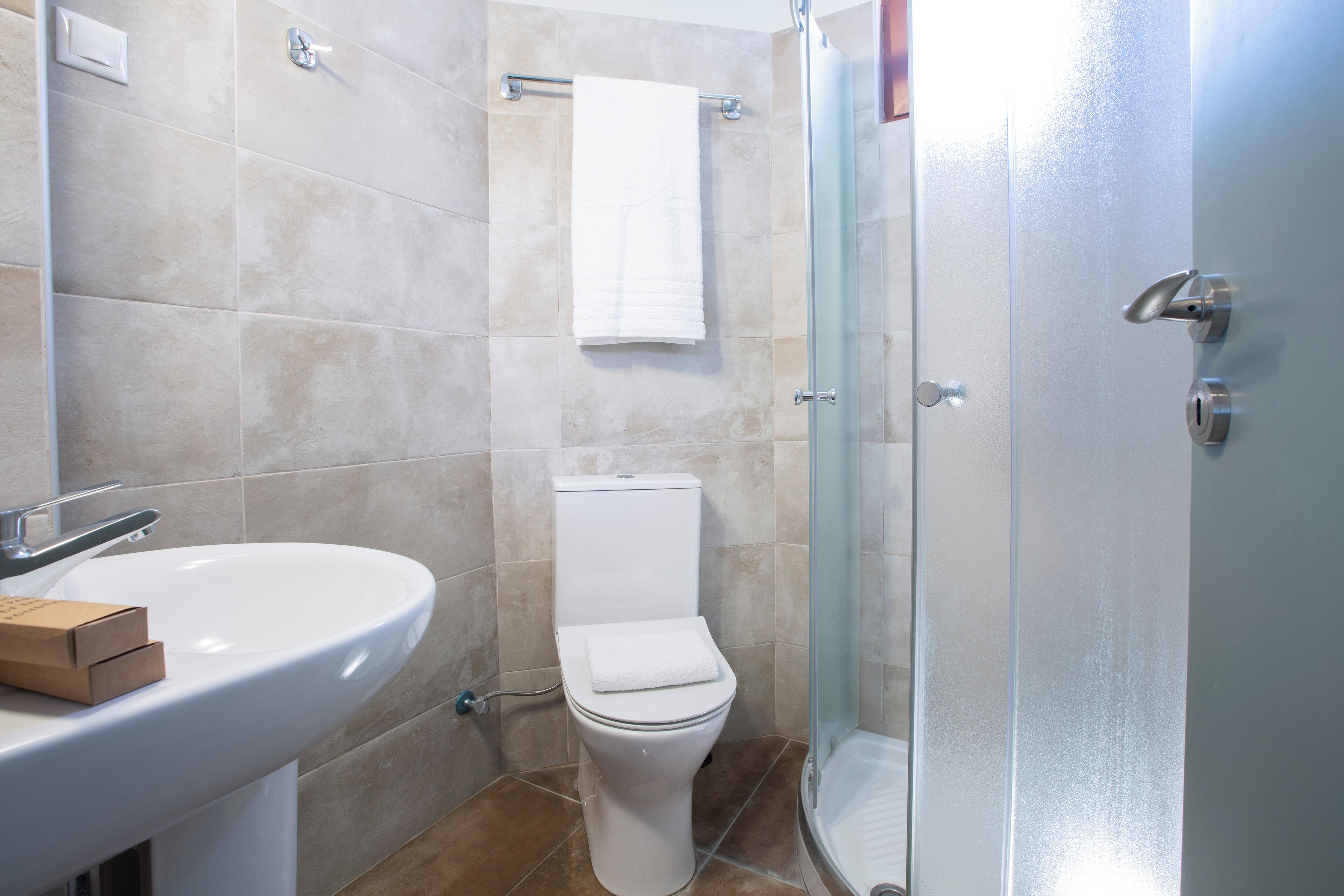A bathroom with a white sink, toilet, and glass shower enclosure.