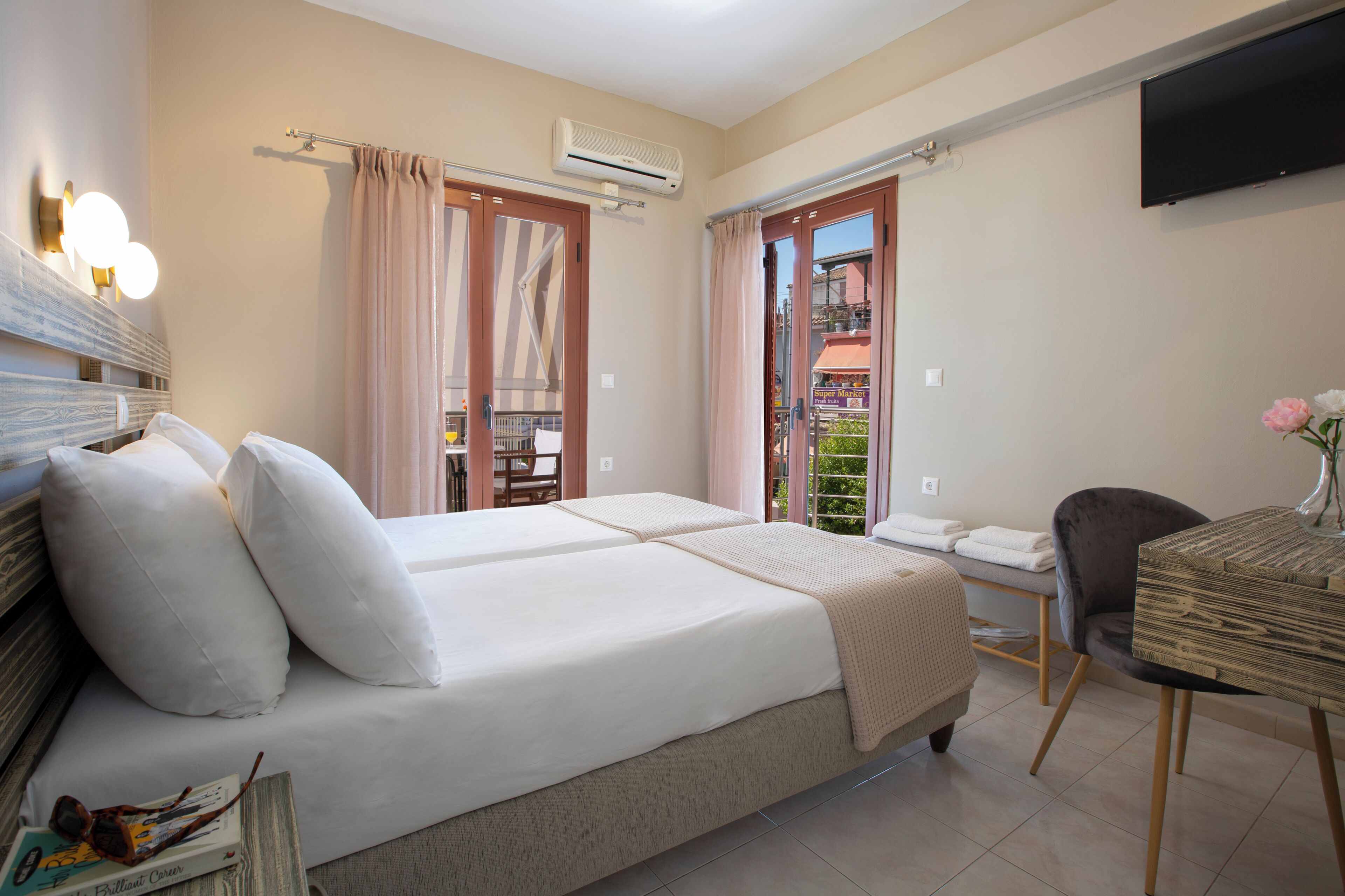 Une chambre d’hôtel avec un lit, un bureau, une chaise, une télévision et un balcon avec vue.