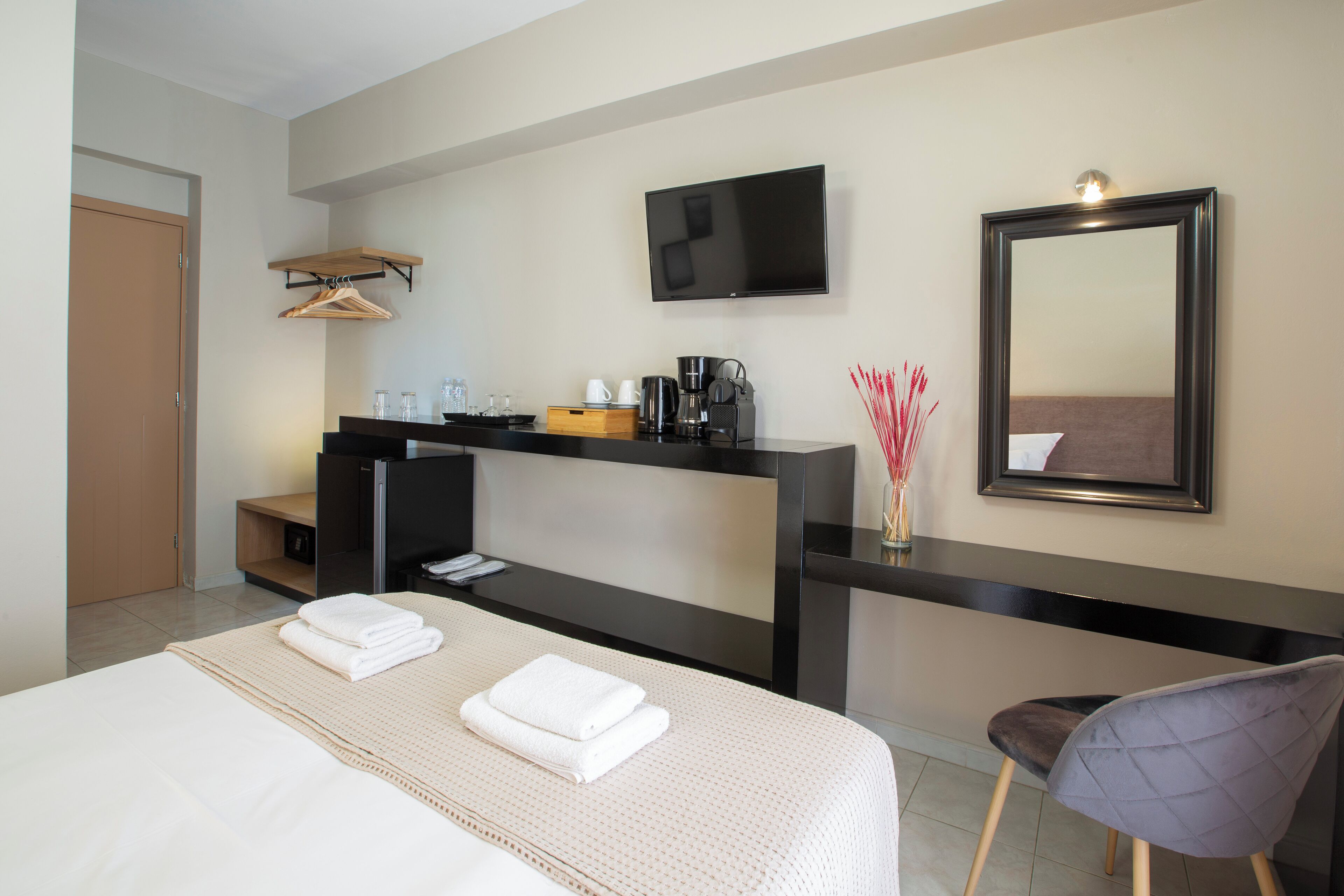 Una habitación de hotel con cama, escritorio, silla, televisor y espejo.