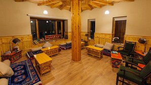 Una habitación acogedora con muebles de madera, un pilar central imponente y un ventanal con vistas al exterior.