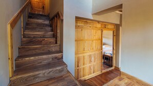 Una escalera de madera que lleva a un dormitorio con puerta de madera.