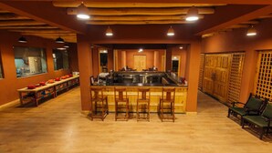 Una cocina amplia con una isla central, taburetes de bar y una zona de estar con sillas.