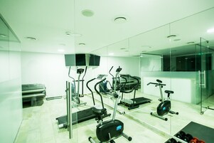 Un gimnasio moderno con máquinas de cardio, pesas libres y un espejo grande.