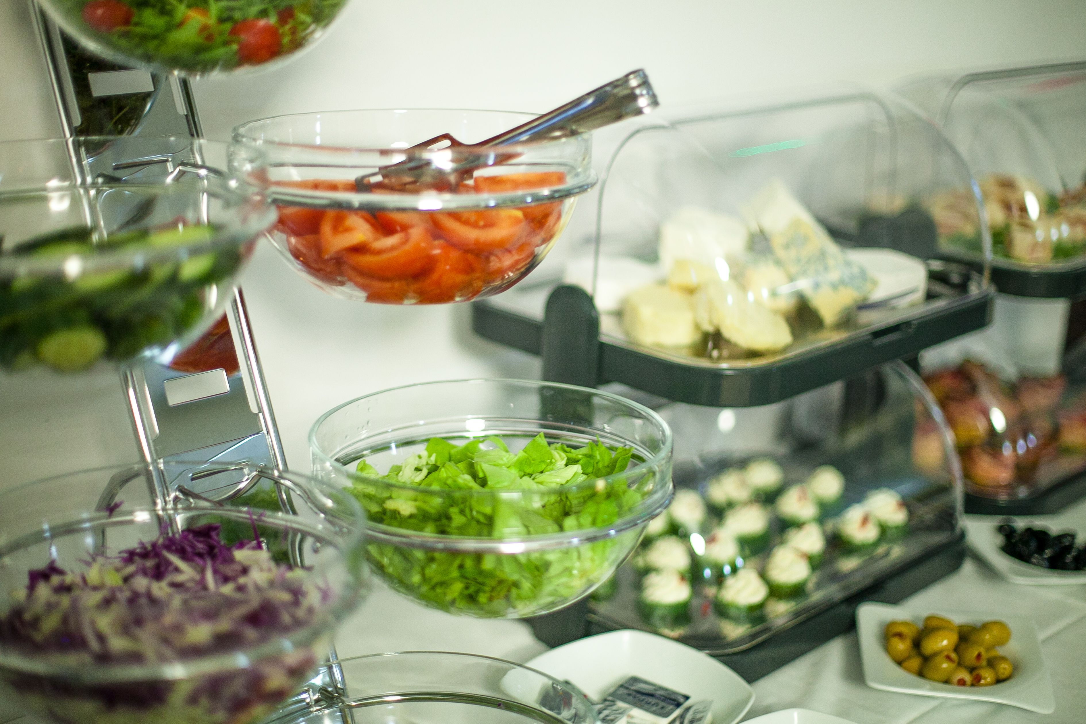 Un bufé con diversas opciones de comida, incluyendo ensaladas, verduras y aperitivos.