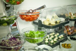 Un bufé con diversas opciones de comida, incluyendo ensaladas, verduras y aperitivos.