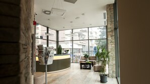 Una moderna zona de recepción con un mostrador curvo, asientos y plantas en macetas.