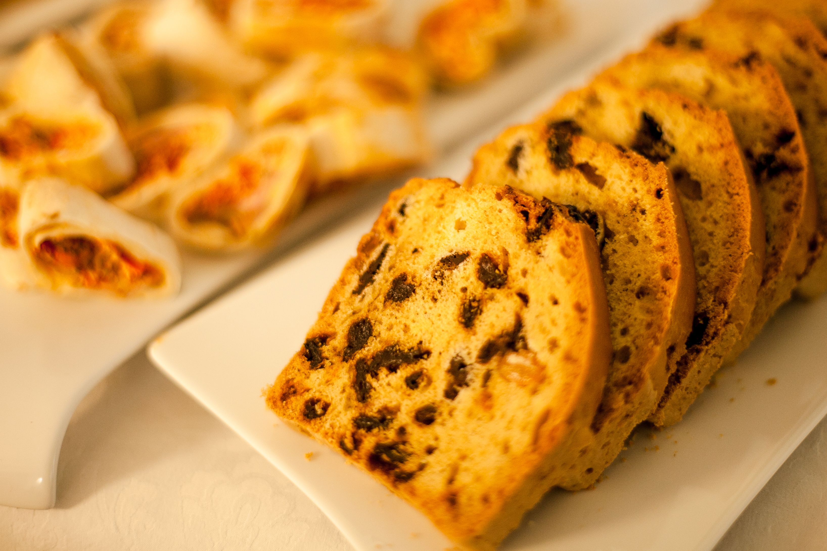 A white rectangular plate with several slices of bread, some with visible dark spots, likely raisins or other ingredients.