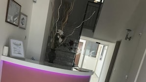 A reception desk with a curved design, a tiled floor, and a staircase in the background. - Romano b&b (Bari)