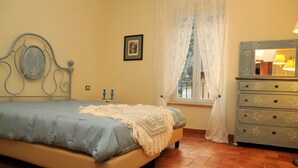 Un dormitorio con cama, cómoda, ventana con cortinas e imagen en la pared.