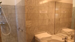 Casa de banho com chuveiro, lavatório e espelho.