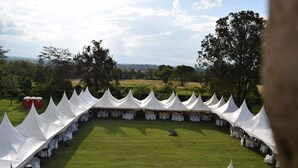 A tented outdoor event area with a grassy lawn and trees in the background. - ARC Egerton Hotel (Njoro)