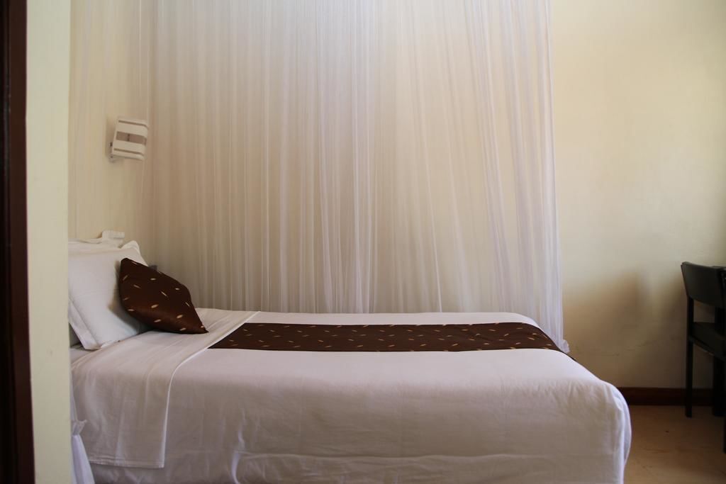 Une chambre d’hôtel avec un lit, une chaise et un rideau.