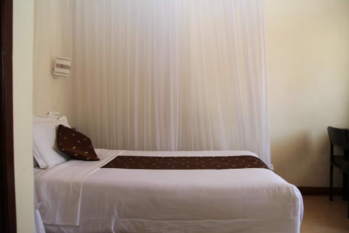 Una habitación de hotel con una cama, una silla y una cortina.