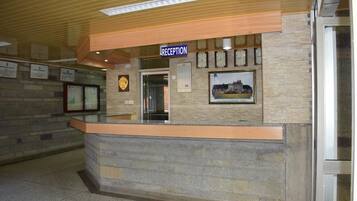 A reception area with a stone wall, a reception desk, a clock, and framed pictures on the wall.