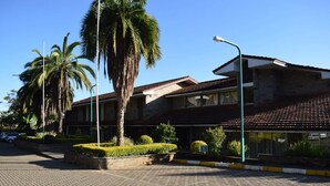 A building with a tiled roof, a paved entrance area, and a wheelchair-accessible sign. - ARC Egerton Hotel (Njoro)