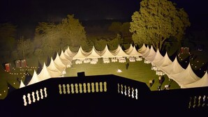 A nighttime outdoor event with tents and tables set up on a grassy field. - ARC Egerton Hotel (Njoro)